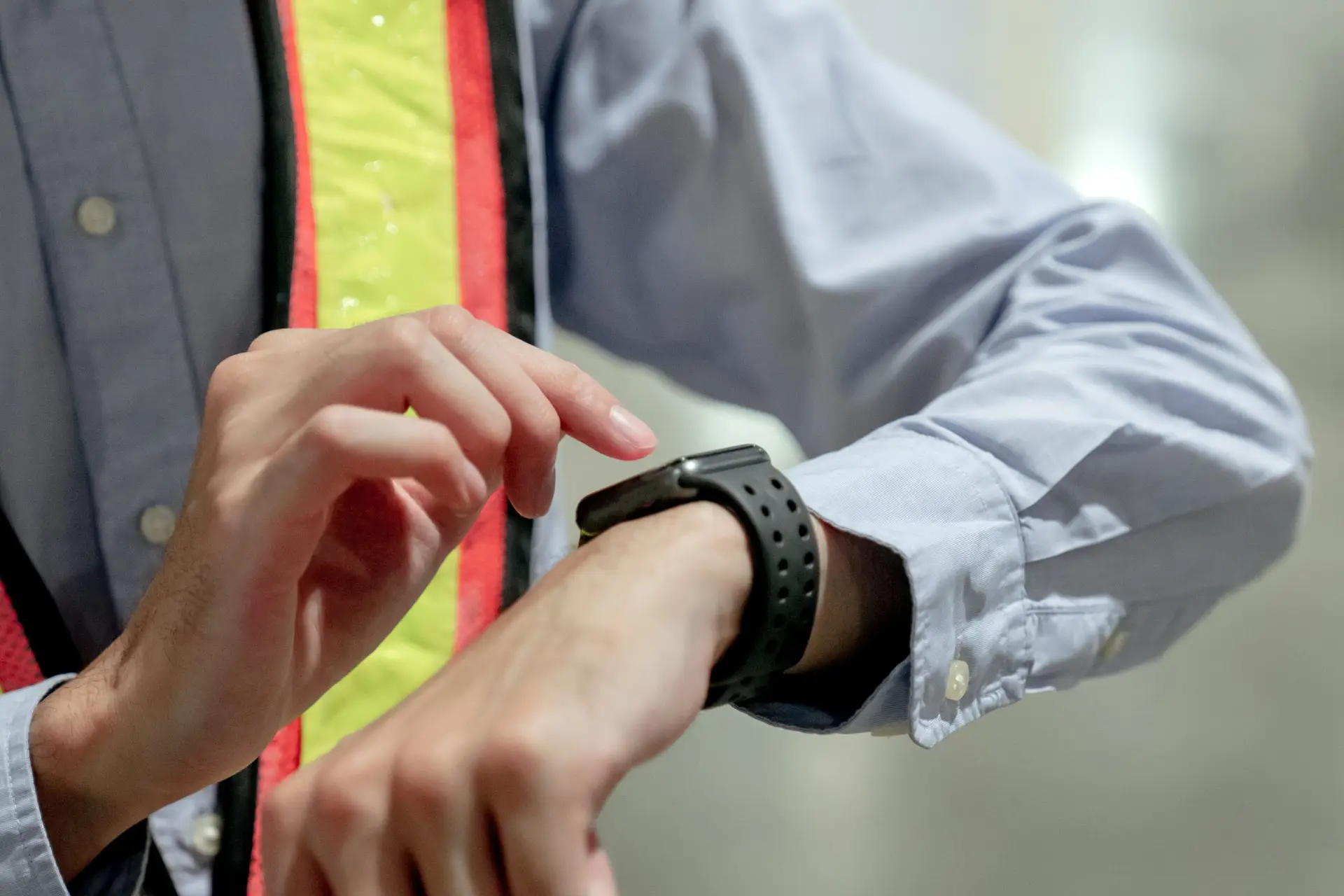 Service worker examining a smartwatch, showcasing wearable technology used for monitoring health metrics and activity, including sleep.